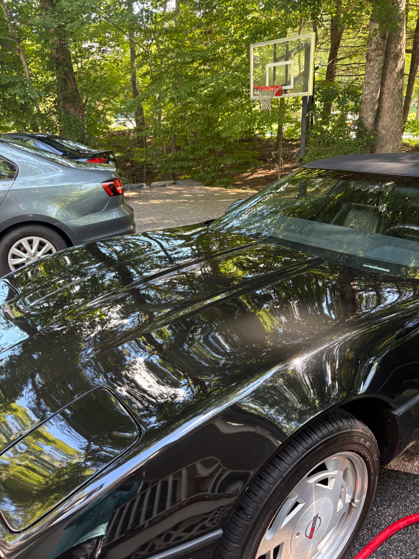 Glossy black Chevrolet Corvette convertible with a deep reflective finish after detailing